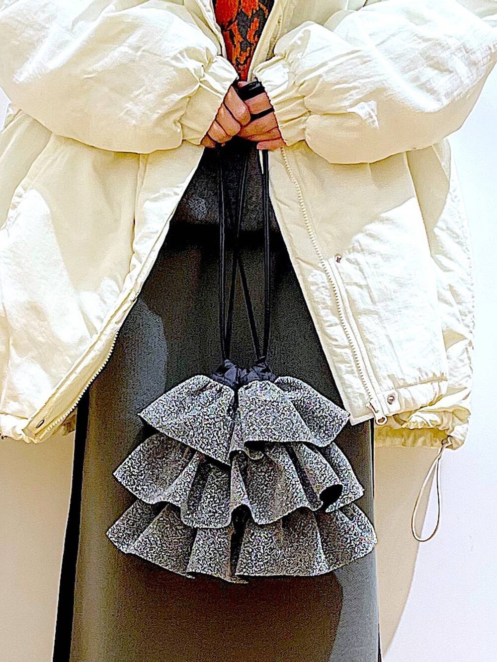 グレー系のスカート、ブラック系のブーツ、ホワイト系のその他アウターを着用したレディースの冬コーディネートの9枚目の写真