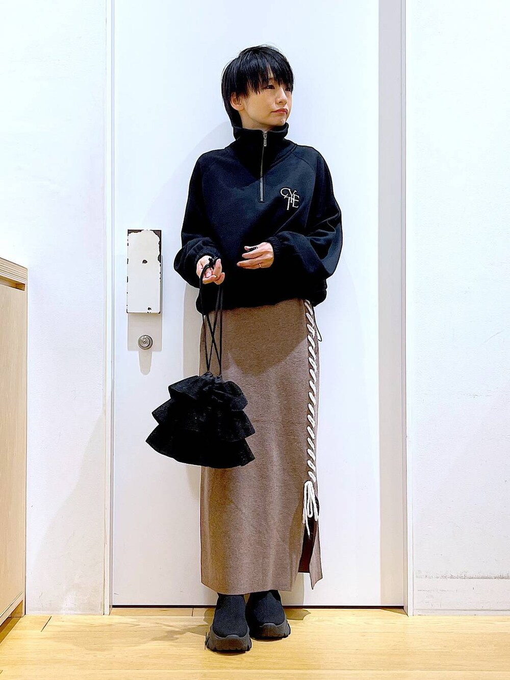 ブラック系のブーツ、ブラウン系のスカート、ブラック系のスウェットを着用したレディースの冬コーディネートの2枚目の写真