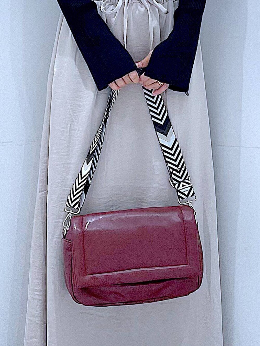 ブラック系のニット/セーター、ベージュ系のスカート、レッド系のショルダーバッグを着用したレディースの秋コーディネートの9枚目の写真