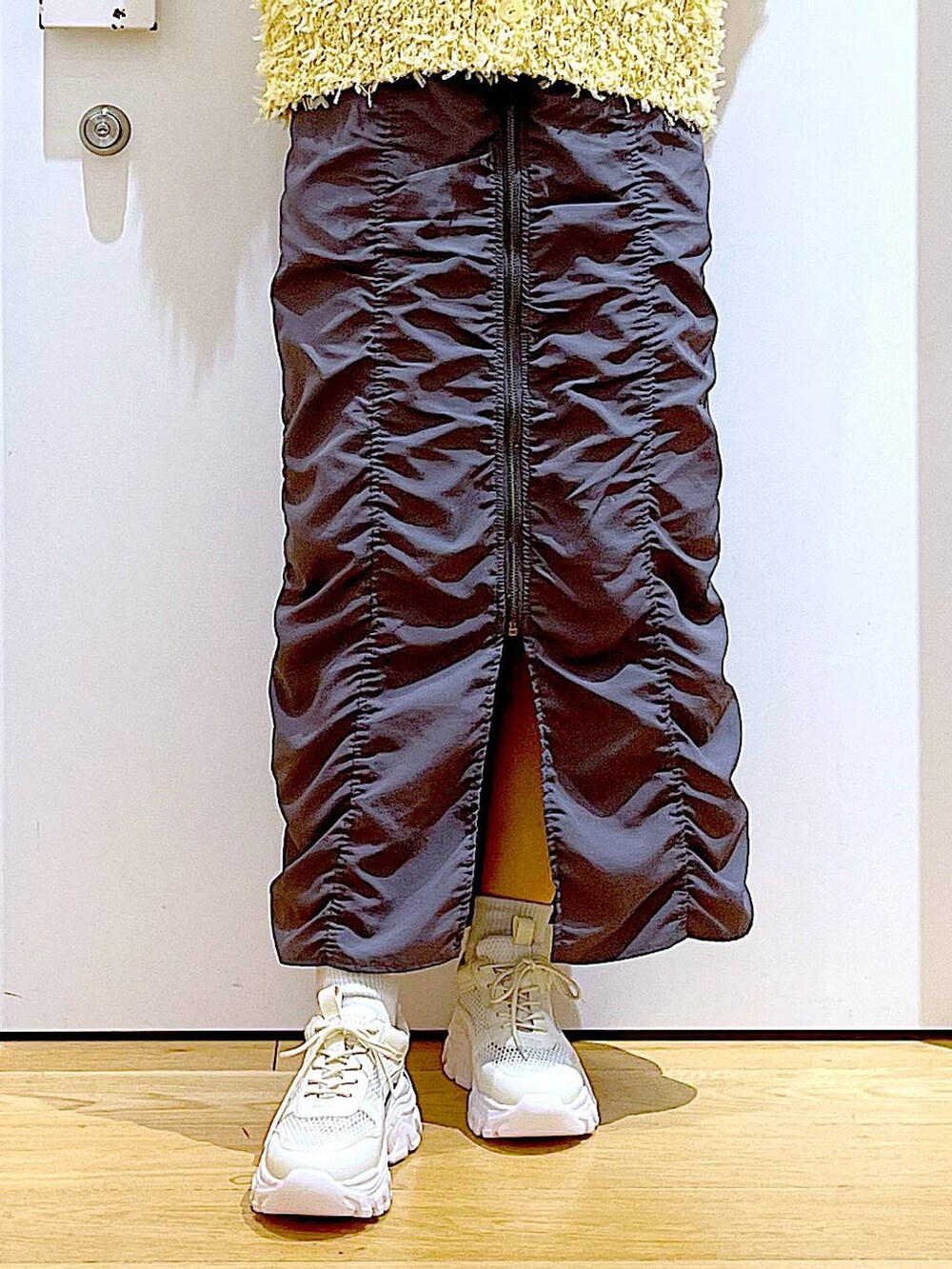 シルバー系のショルダーバッグ、グレー系のスカート、ホワイト系のスニーカーを着用したレディースの春コーディネートの8枚目の写真