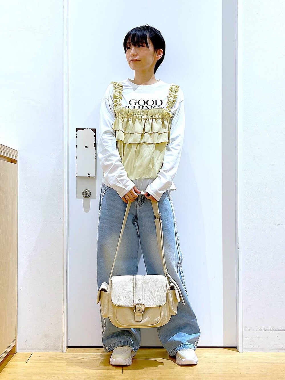 ホワイト系のスニーカー、ブルー系のデニムパンツ、ベージュ系のその他トップスを着用したレディースの春コーディネートの2枚目の写真