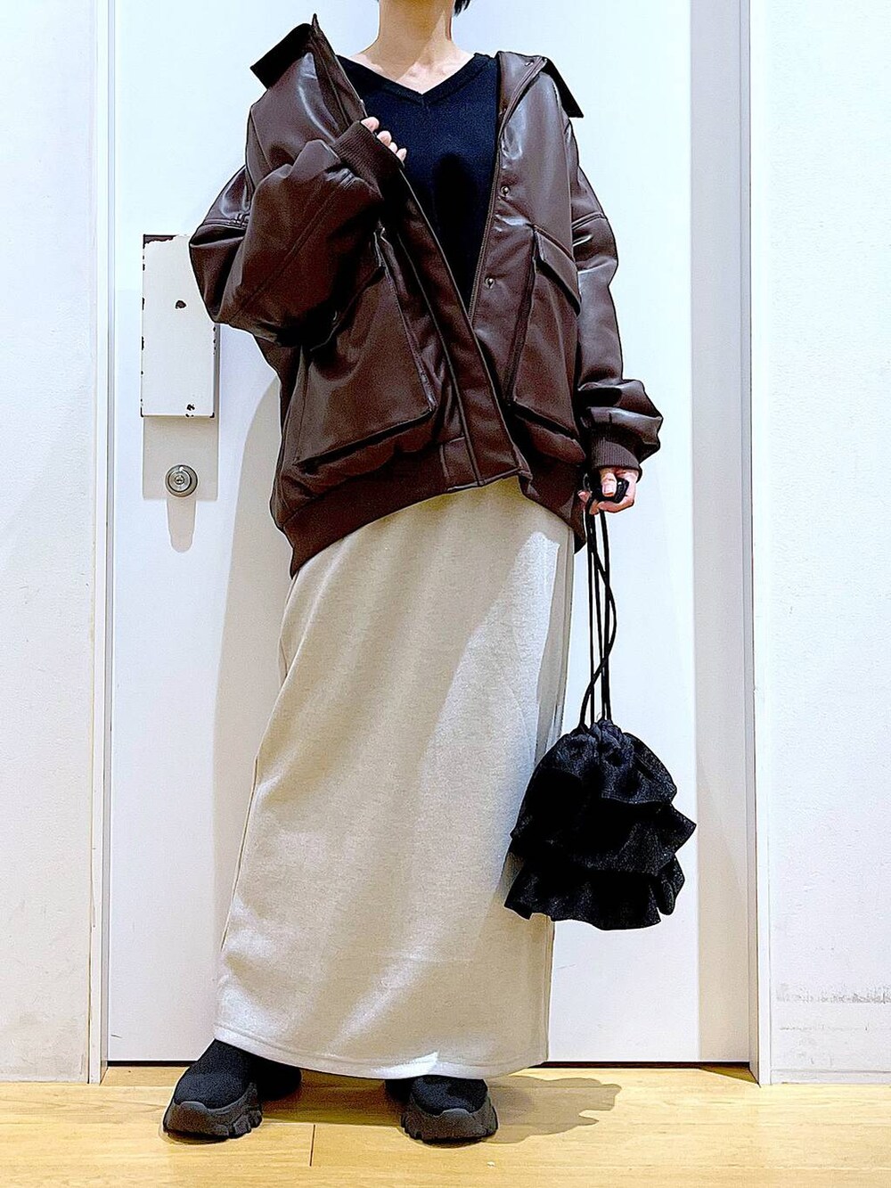 ブラウン系のブルゾン、ブラック系のブーツ、ブラック系のショルダーバッグを着用したレディースの冬コーディネートの6枚目の写真