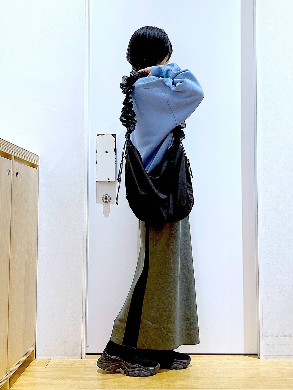 ブルー系のニット/セーター、ブラック系のショルダーバッグ、グレー系のスカートを着用したレディースの冬コーディネートの4枚目の写真