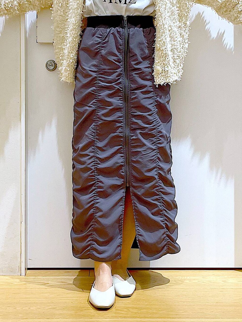 グレー系のスカート、ホワイト系のショルダーバッグ、ホワイト系のパンプスを着用したレディースの春コーディネートの8枚目の写真