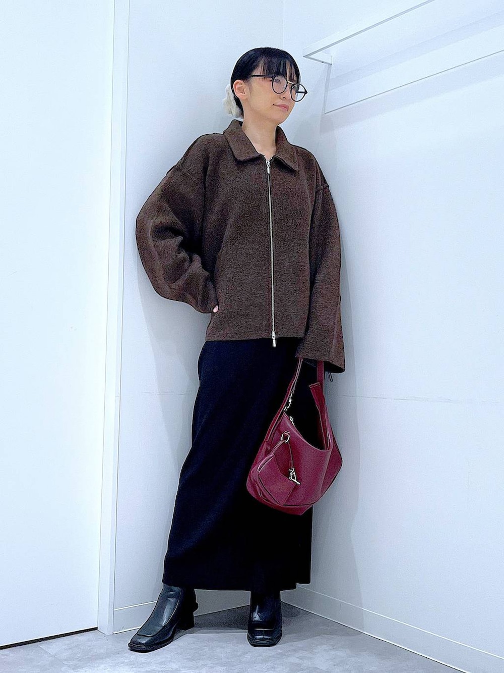 ブラウン系のブルゾン、ブラック系のブーツ、レッド系のショルダーバッグを着用したレディースの秋コーディネートの2枚目の写真