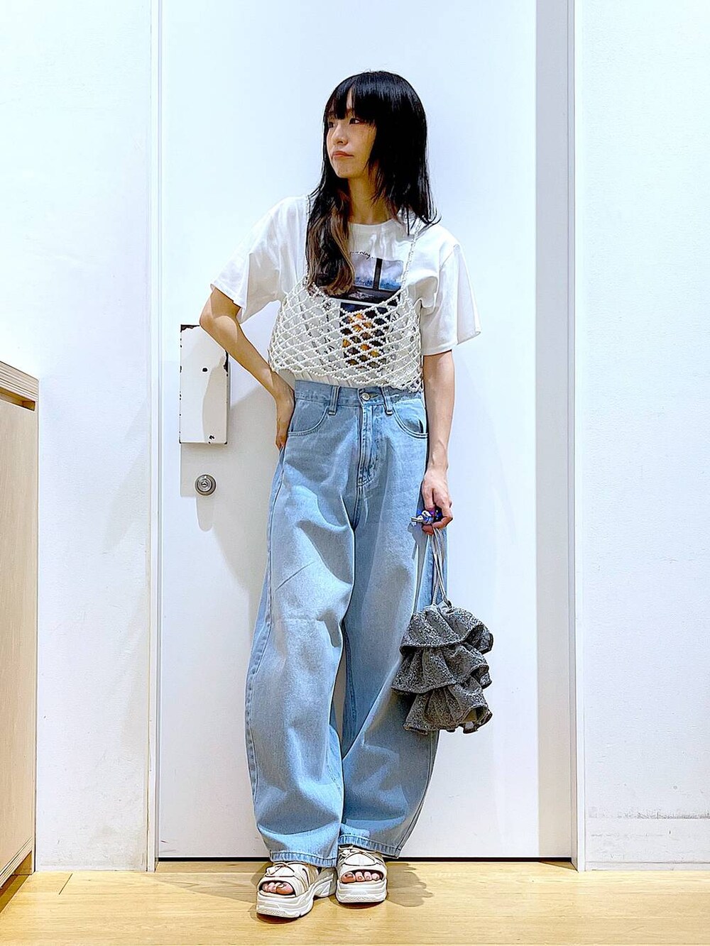 シルバー系のショルダーバッグ、ベージュ系のサンダル、ブルー系のデニムパンツを着用したレディースの夏コーディネートの2枚目の写真