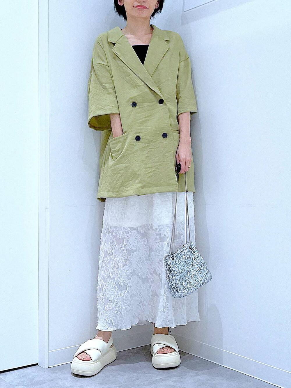 シルバー系のショルダーバッグ、ホワイト系のサンダル、グリーン系のテーラードジャケットを着用したレディースの夏コーディネートの6枚目の写真
