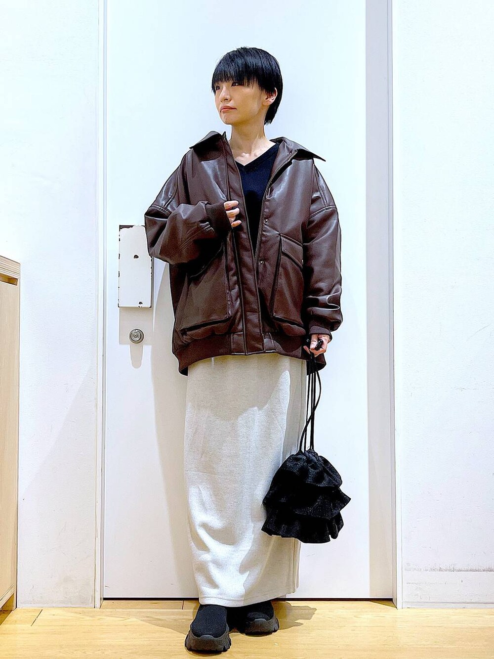 ブラウン系のブルゾン、ブラック系のブーツ、ブラック系のショルダーバッグを着用したレディースの冬コーディネートの2枚目の写真