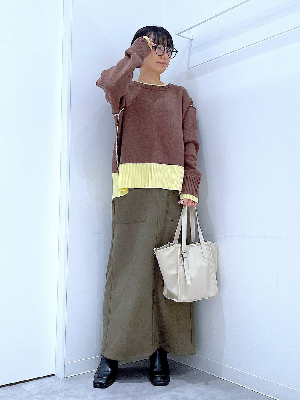 ブラック系のブーツ、グリーン系のスカート、ホワイト系のトートバッグを着用したレディースの冬コーディネートの2枚目の写真