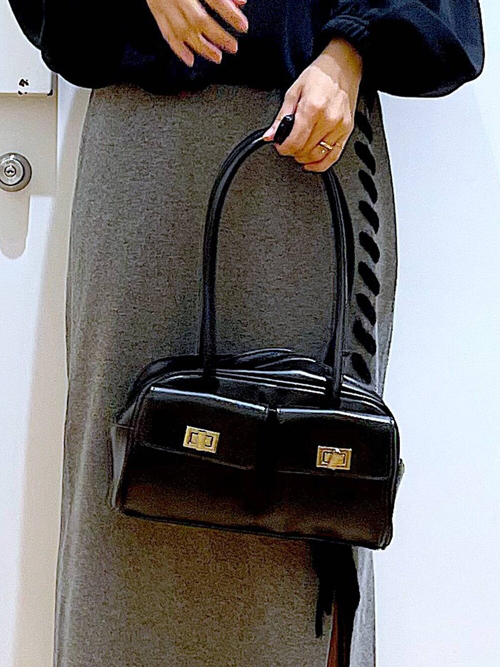 ブラック系のハンドバッグ、ブラック系のブーツ、グレー系のスカートを着用したレディースの冬コーディネートの9枚目の写真