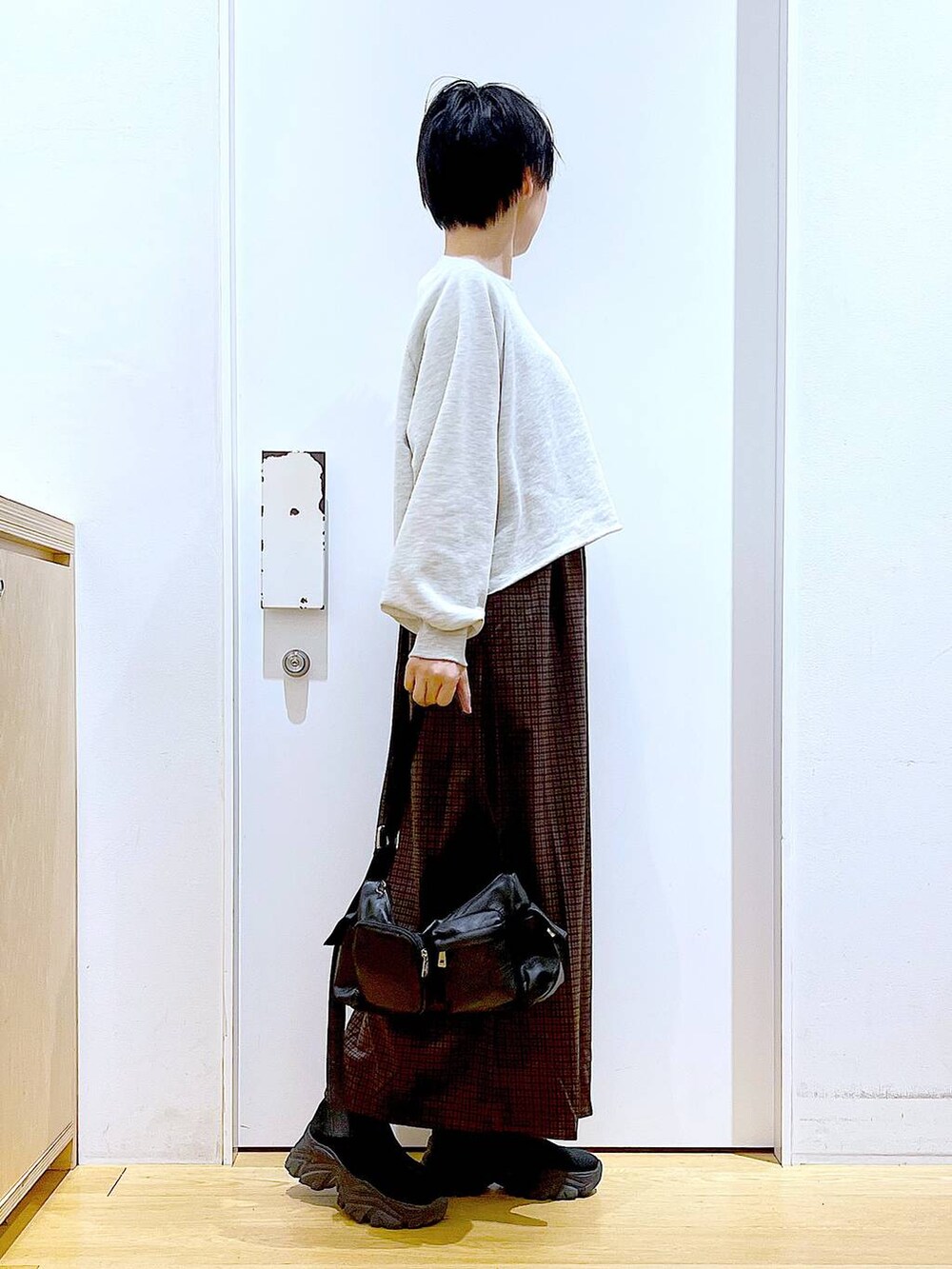 ブラック系のブーツ、ブラック系のショルダーバッグ、ブラウン系のワンピースを着用したレディースの冬コーディネートの4枚目の写真