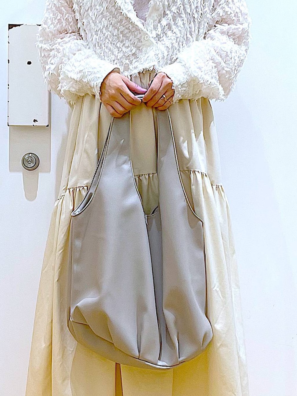 グレー系のトートバッグ、ホワイト系のシャツ/ブラウス、ベージュ系のスニーカーを着用したレディースの春コーディネートの9枚目の写真