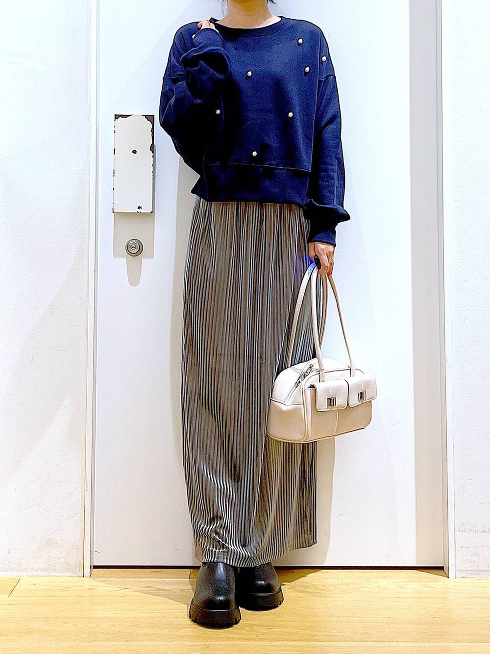ホワイト系のハンドバッグ、ブラック系のブーツ、ブルー系のスウェットを着用したレディースの秋コーディネートの6枚目の写真