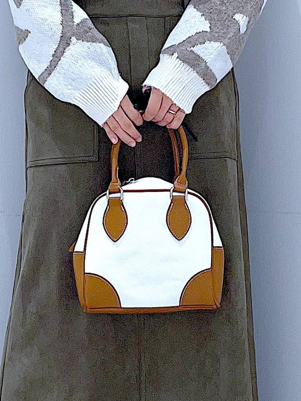 ブラック系のブーツ、ホワイト系のハンドバッグ、グリーン系のスカートを着用したレディースの秋コーディネートの9枚目の写真