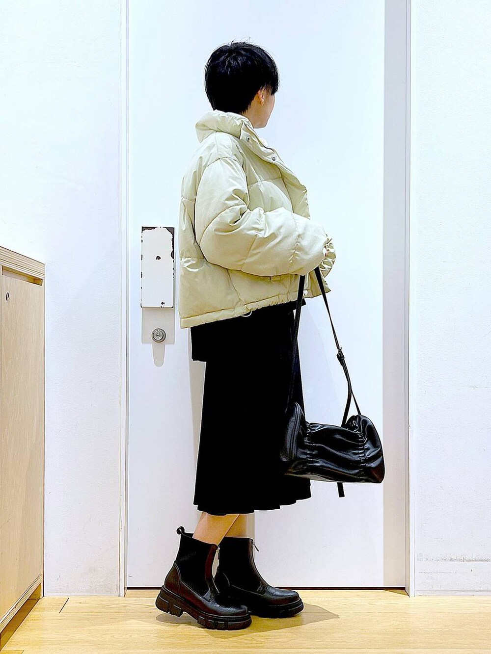 イエロー系のブルゾン、ブラック系のブーツ、ブラック系のスカートを着用したレディースの冬コーディネートの4枚目の写真