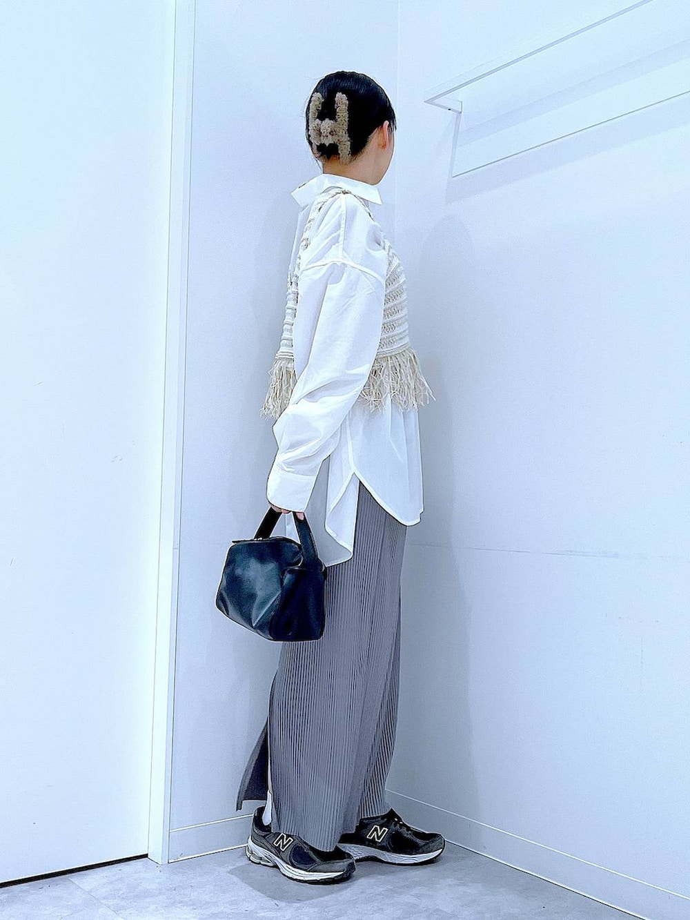 ブラック系のショルダーバッグ、ベージュ系のベスト、グレー系のスカートを着用したレディースの春コーディネートの4枚目の写真