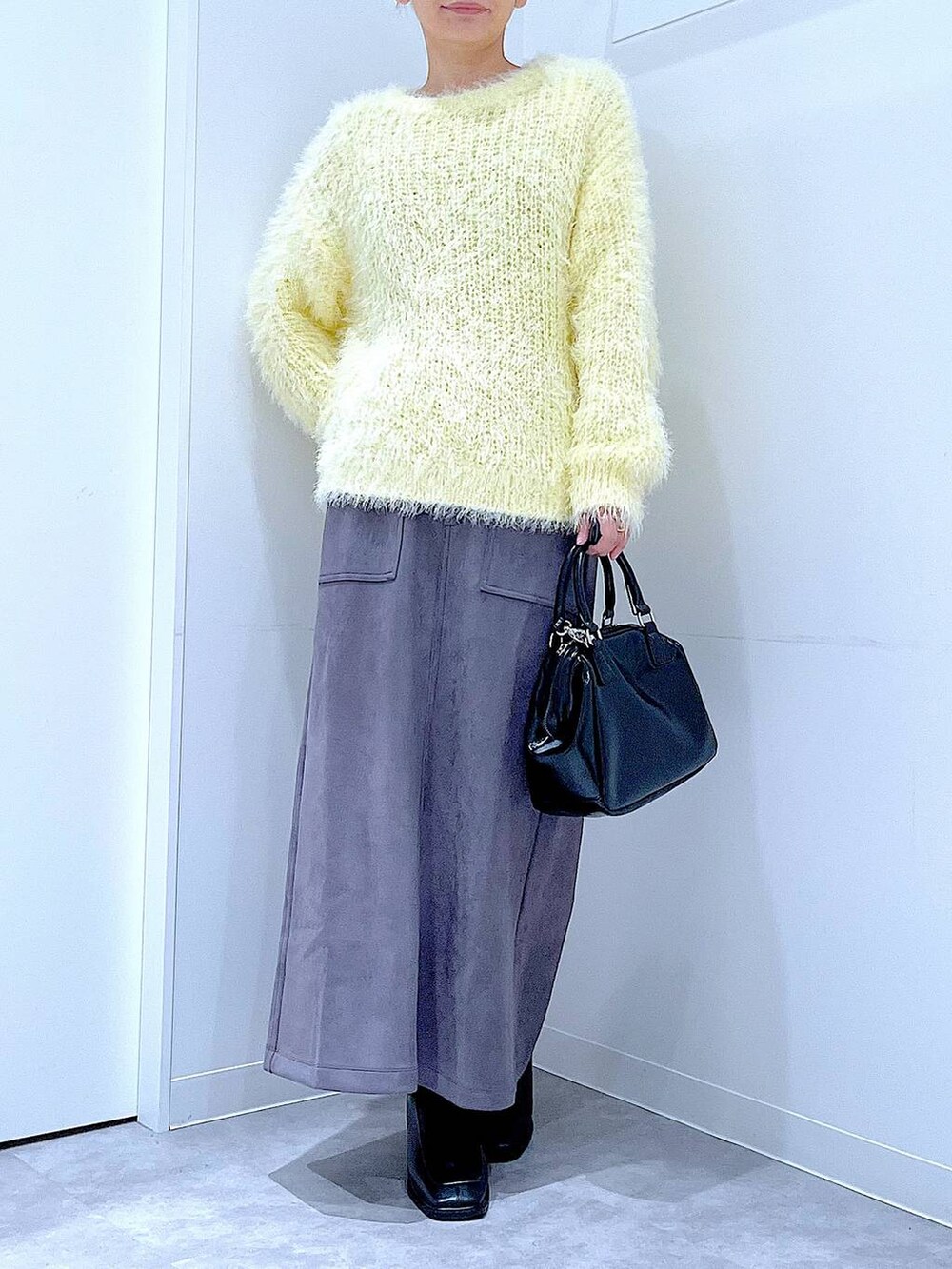 ブラック系のブーツ、イエロー系のニット/セーター、ブラック系のショルダーバッグを着用したレディースの冬コーディネートの6枚目の写真