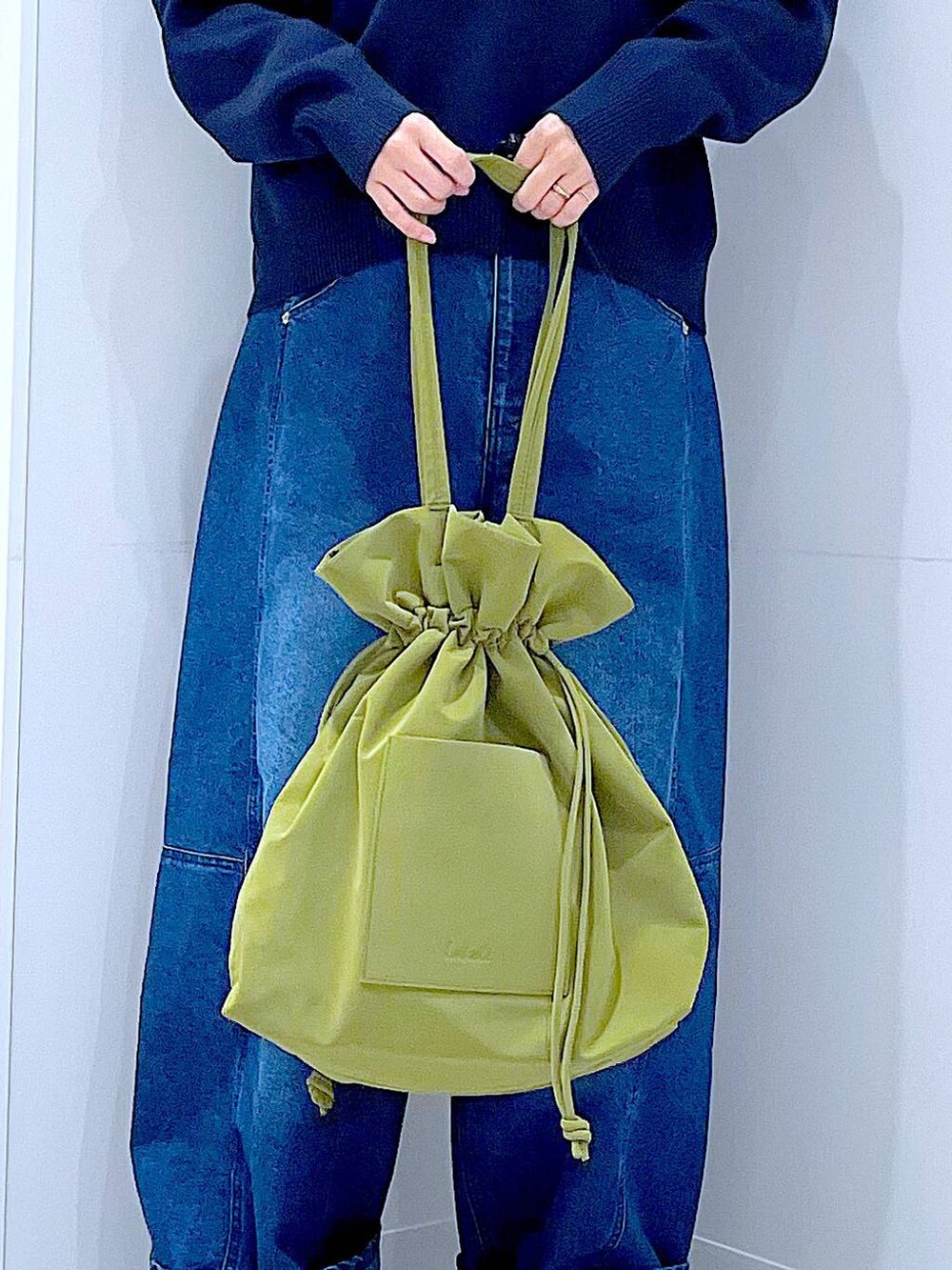 グリーン系のトートバッグ、ブルー系のニット/セーター、ブルー系のデニムパンツを着用したレディースの冬コーディネートの9枚目の写真