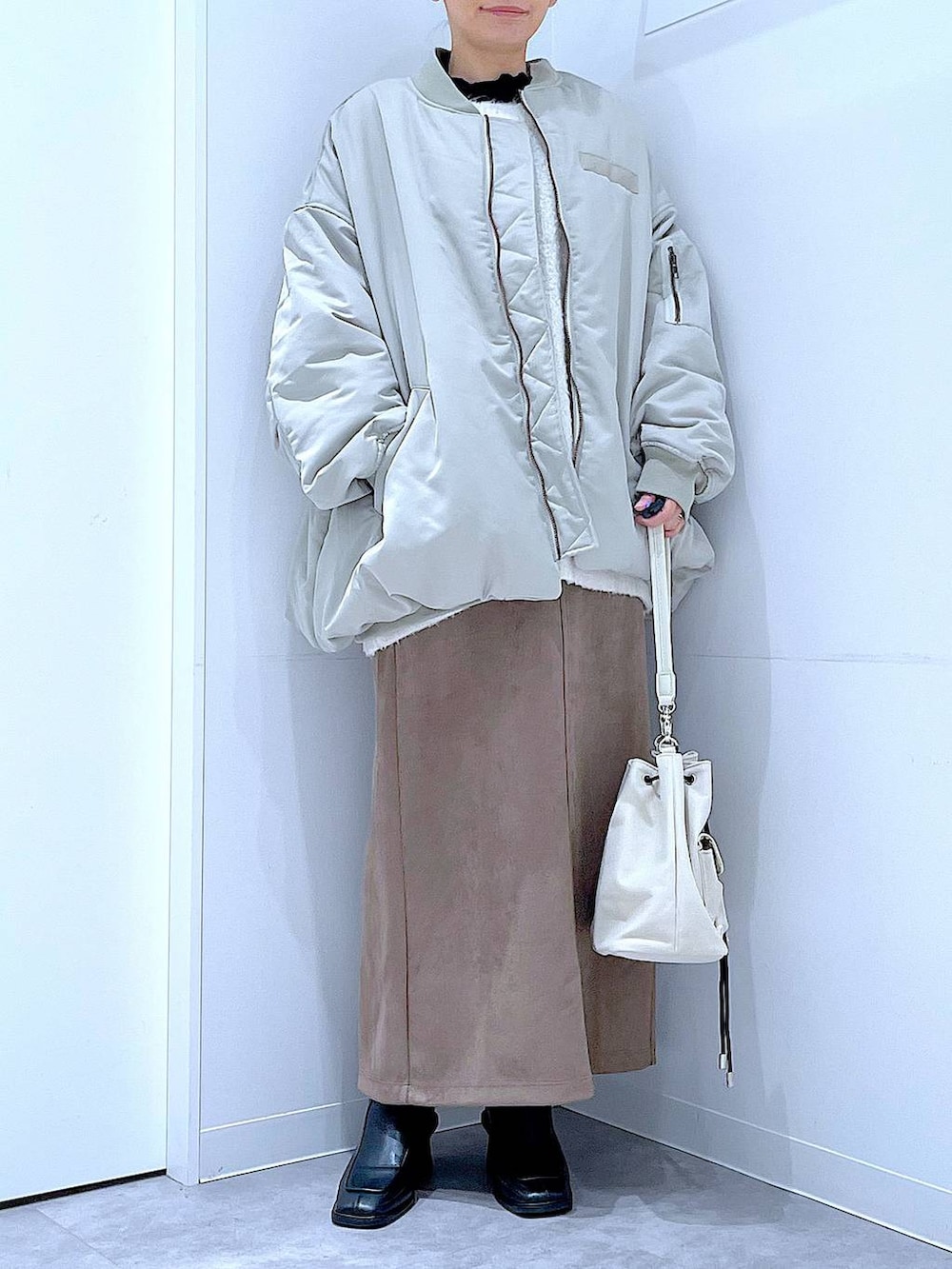 ベージュ系のニット/セーター、ブラック系のブーツ、ブラウン系のスカートを着用したレディースの冬コーディネートの6枚目の写真