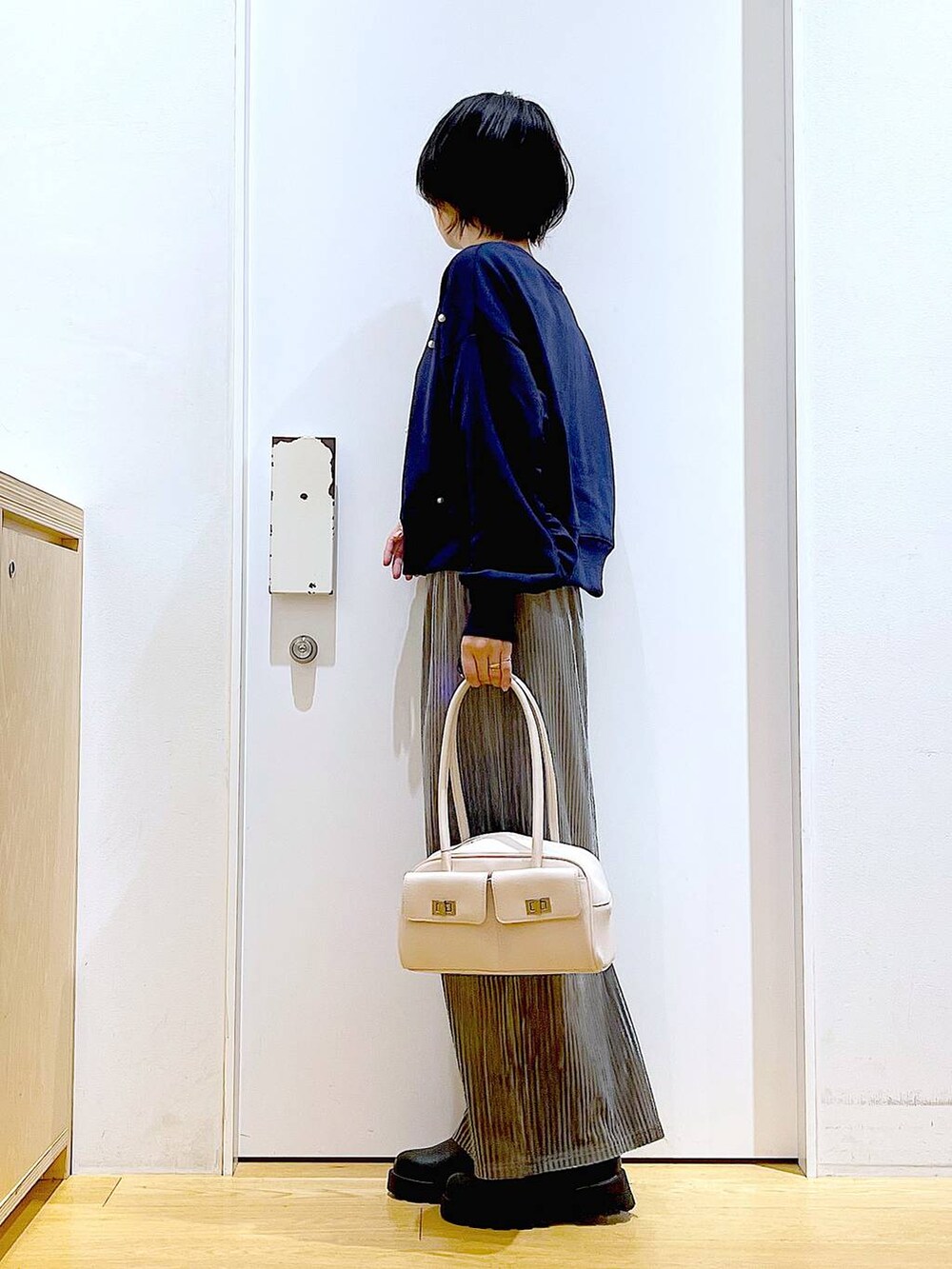 ホワイト系のハンドバッグ、ブラック系のブーツ、ブルー系のスウェットを着用したレディースの秋コーディネートの3枚目の写真