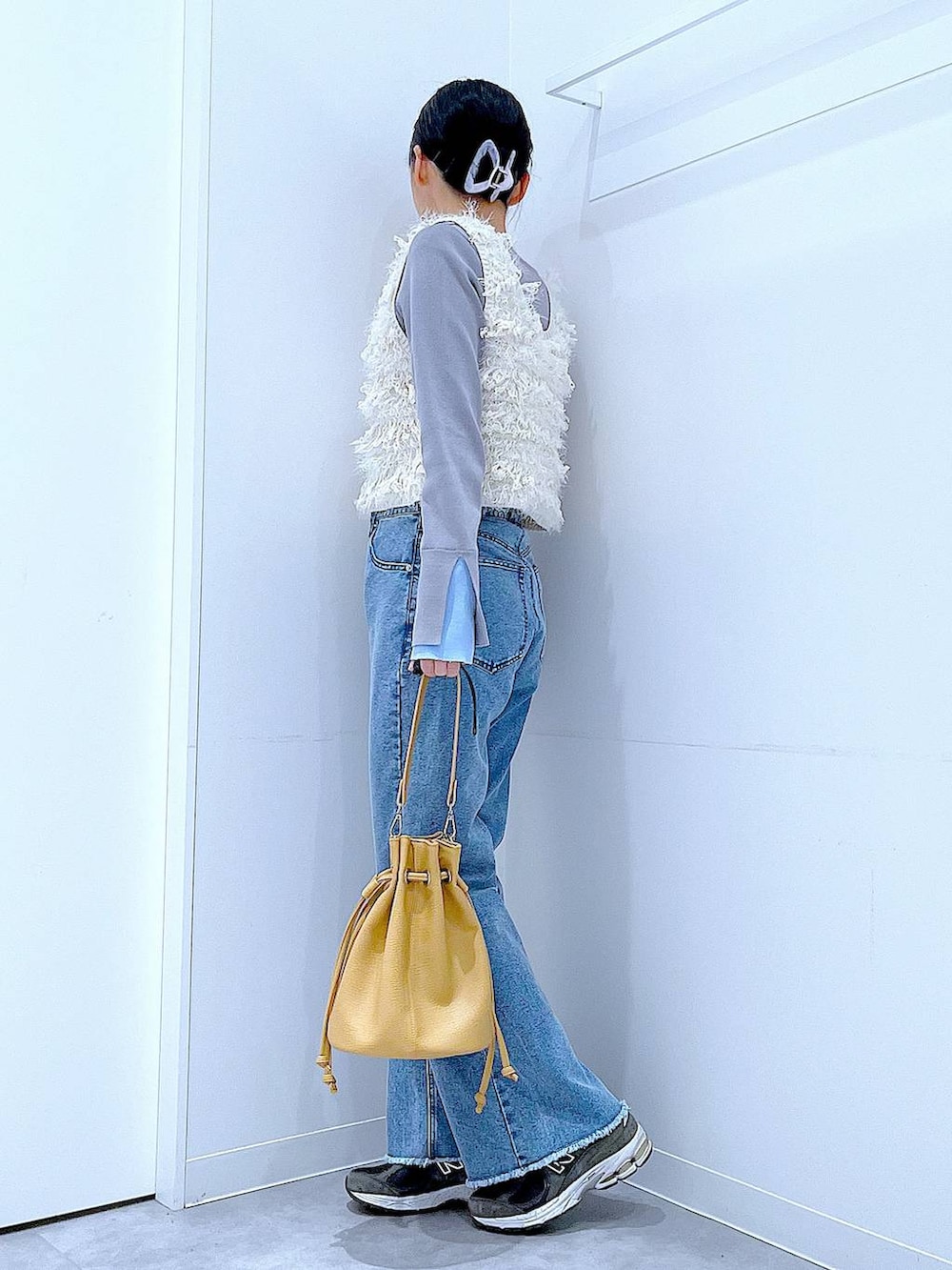 ホワイト系のベスト、グレー系のニット/セーター、ブルー系のデニムパンツを着用したレディースの春コーディネートの3枚目の写真