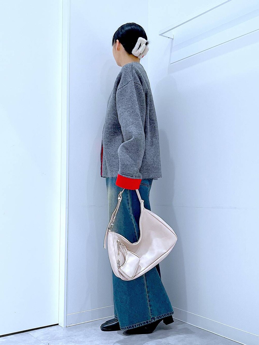 ブルー系のデニムパンツ、ブラック系のブーツ、ホワイト系のショルダーバッグを着用したレディースの冬コーディネートの3枚目の写真