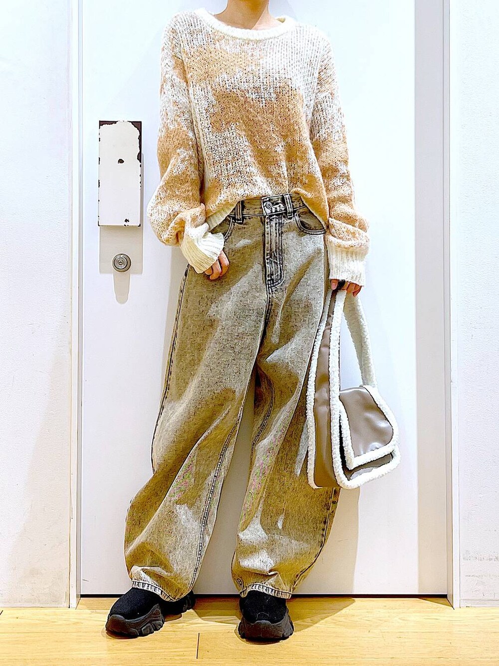 ブラック系のブーツ、ベージュ系のショルダーバッグ、ベージュ系のデニムパンツを着用したレディースの冬コーディネートの6枚目の写真