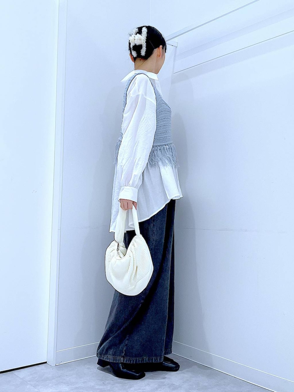 ブラック系のブーツ、ブルー系のベスト、ホワイト系のショルダーバッグを着用したレディースの春コーディネートの4枚目の写真