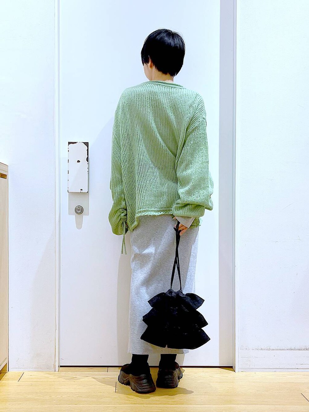 ブラック系のブーツ、グリーン系のニット/セーター、グレー系のスカートを着用したレディースの冬コーディネートの5枚目の写真