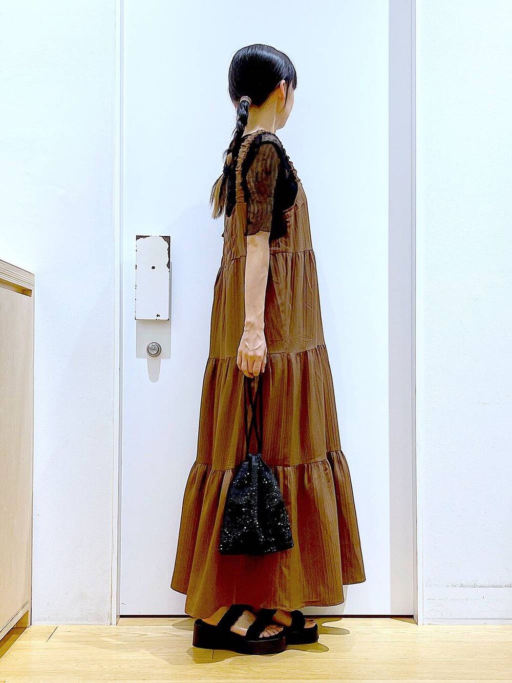 ブラック系のサンダル、ブラック系のショルダーバッグ、ベージュ系のワンピースを着用したレディースの夏コーディネートの4枚目の写真