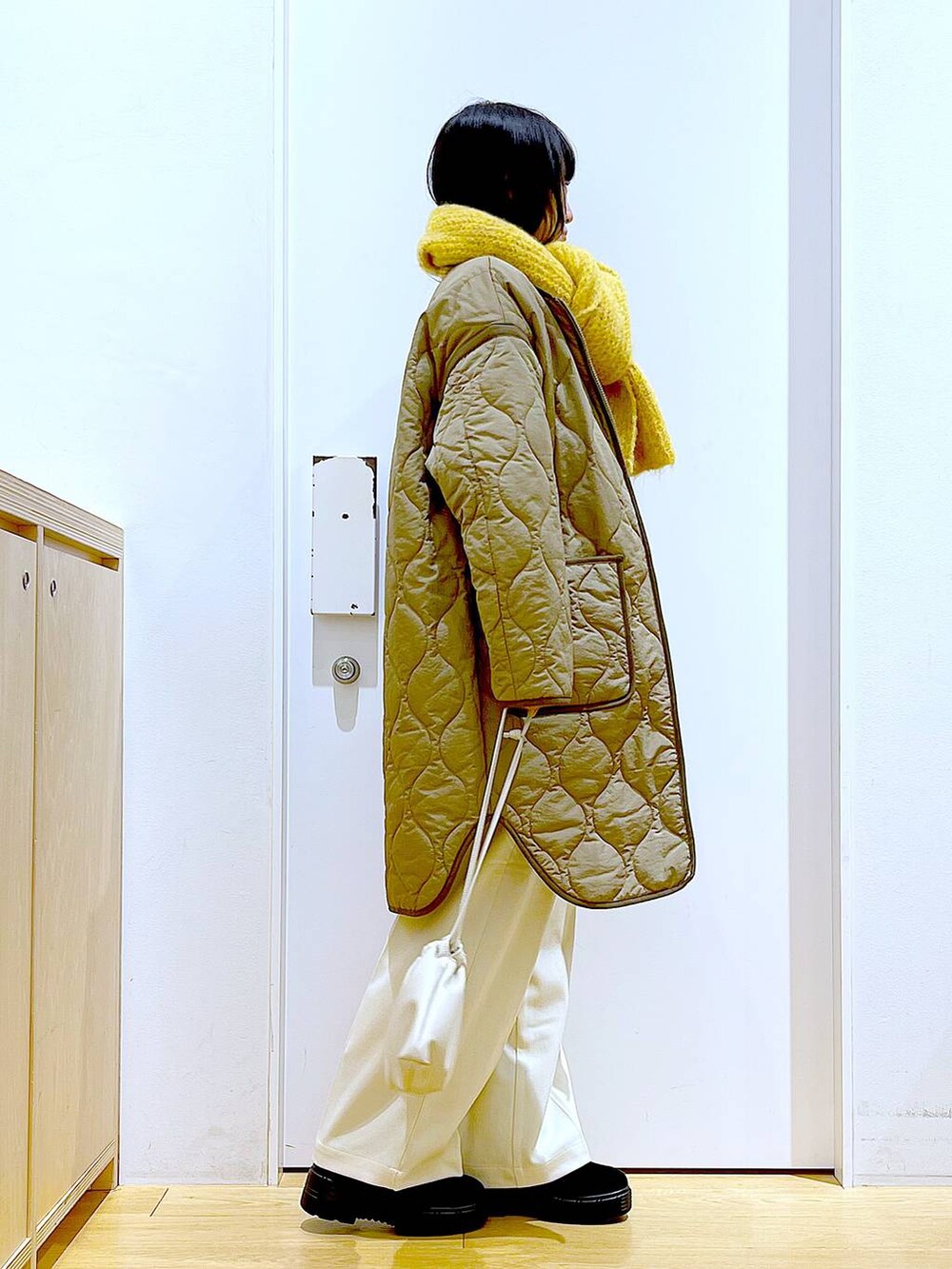 グリーン系のナイロンジャケット、ベージュ系のショルダーバッグ、ブラック系のブーツを着用したレディースの冬コーディネートの4枚目の写真