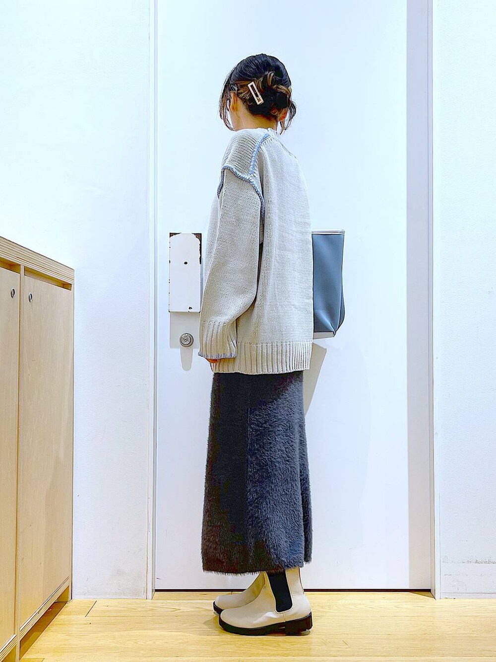 グレー系のトートバッグ、ベージュ系のブーツ、グレー系のスカートを着用したレディースの冬コーディネートの3枚目の写真