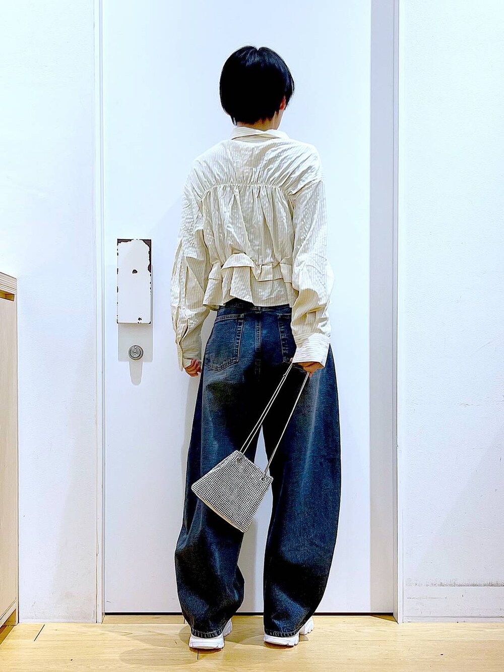 グレー系のショルダーバッグ、ブルー系のデニムパンツ、ホワイト系のスニーカーを着用したレディースの春コーディネートの5枚目の写真