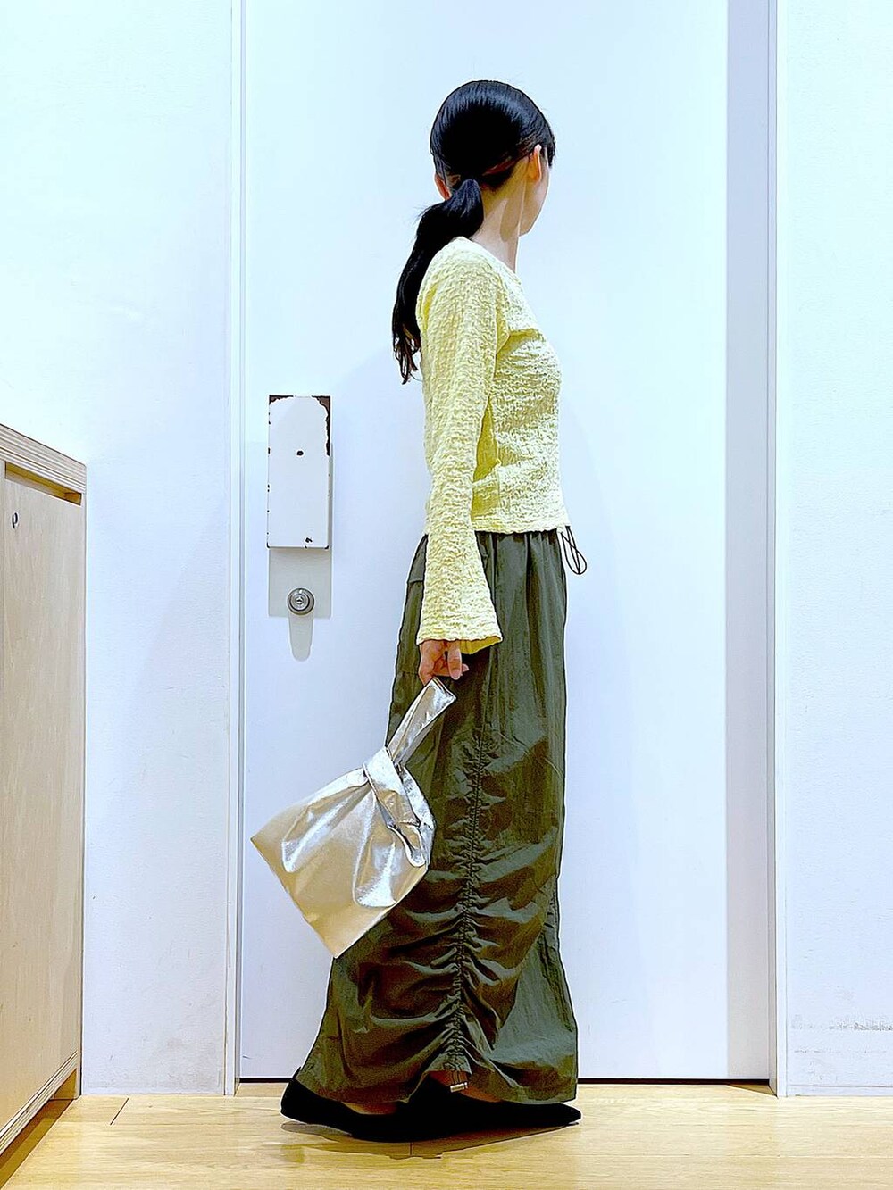 シルバー系のショルダーバッグ、グリーン系のスカート、ブラック系のパンプスを着用したレディースの春コーディネートの4枚目の写真