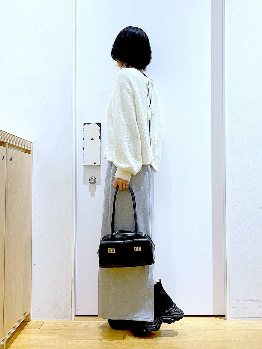 ブラック系のハンドバッグ、ブラック系のブーツ、グレー系のスカートを着用したレディースの冬コーディネートの3枚目の写真