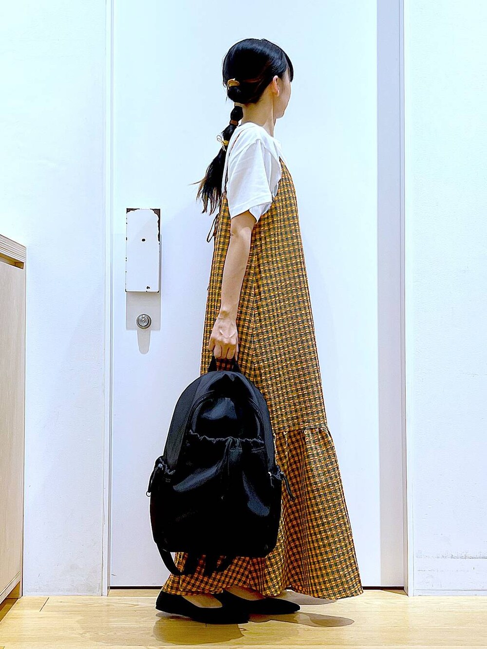 オレンジ系のワンピース、ブラック系のバックパック/リュック、ブラック系のパンプスを着用したレディースの春コーディネートの4枚目の写真