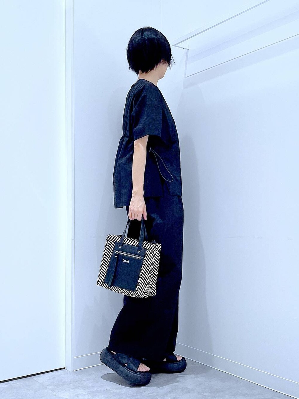 ブラック系のショルダーバッグ、ブラック系のサンダル、ブラック系のTシャツ/カットソーを着用したレディースの夏コーディネートの4枚目の写真