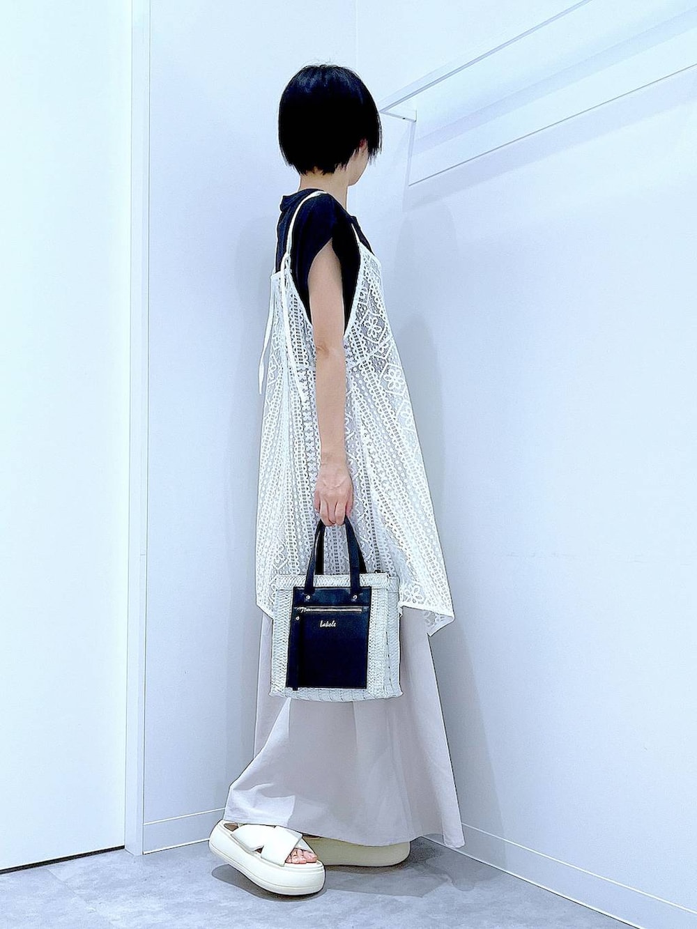 ホワイト系のショルダーバッグ、ホワイト系のサンダル、ブラック系のTシャツ/カットソーを着用したレディースの夏コーディネートの4枚目の写真