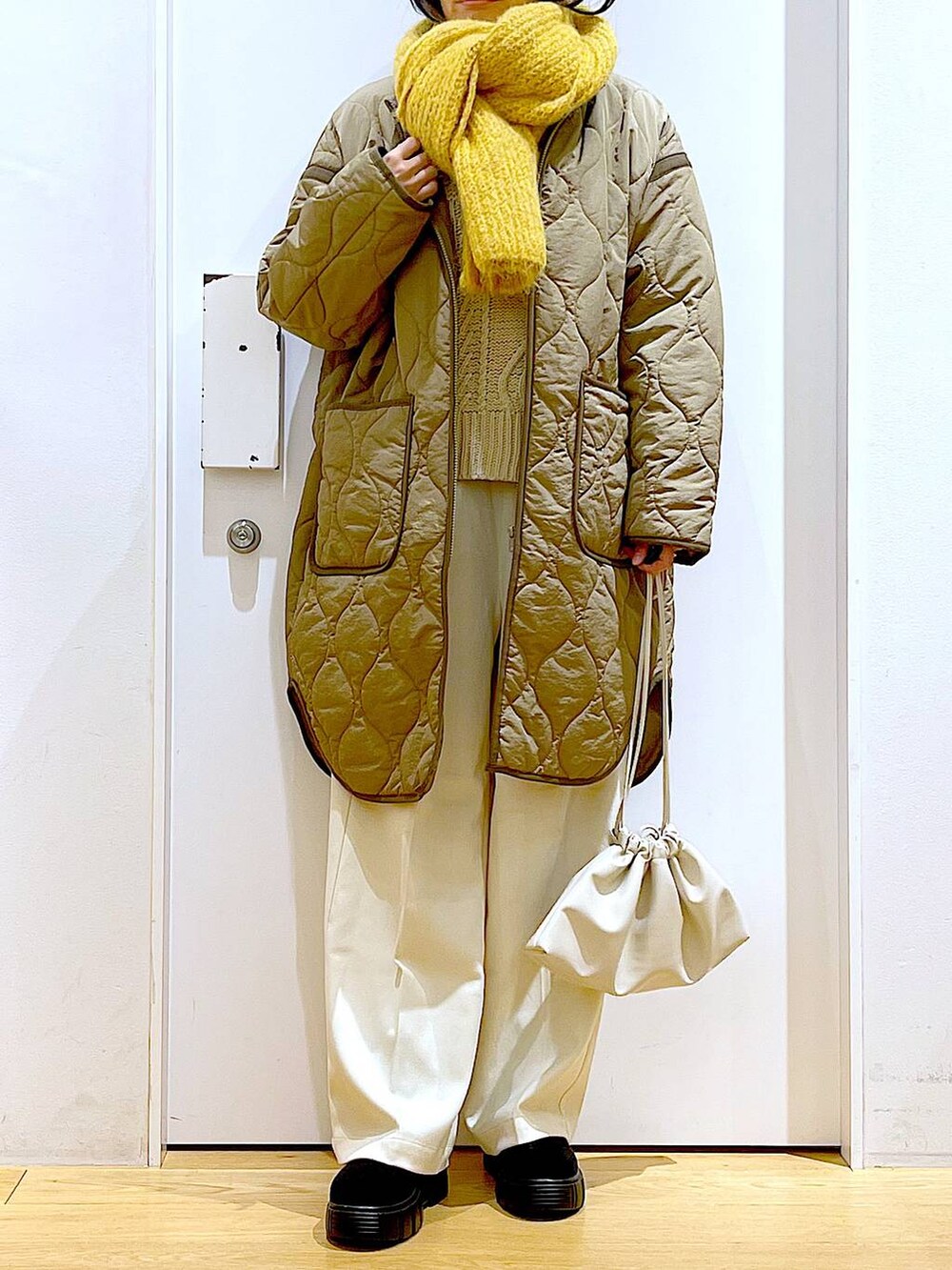 グリーン系のナイロンジャケット、ベージュ系のショルダーバッグ、ブラック系のブーツを着用したレディースの冬コーディネートの6枚目の写真