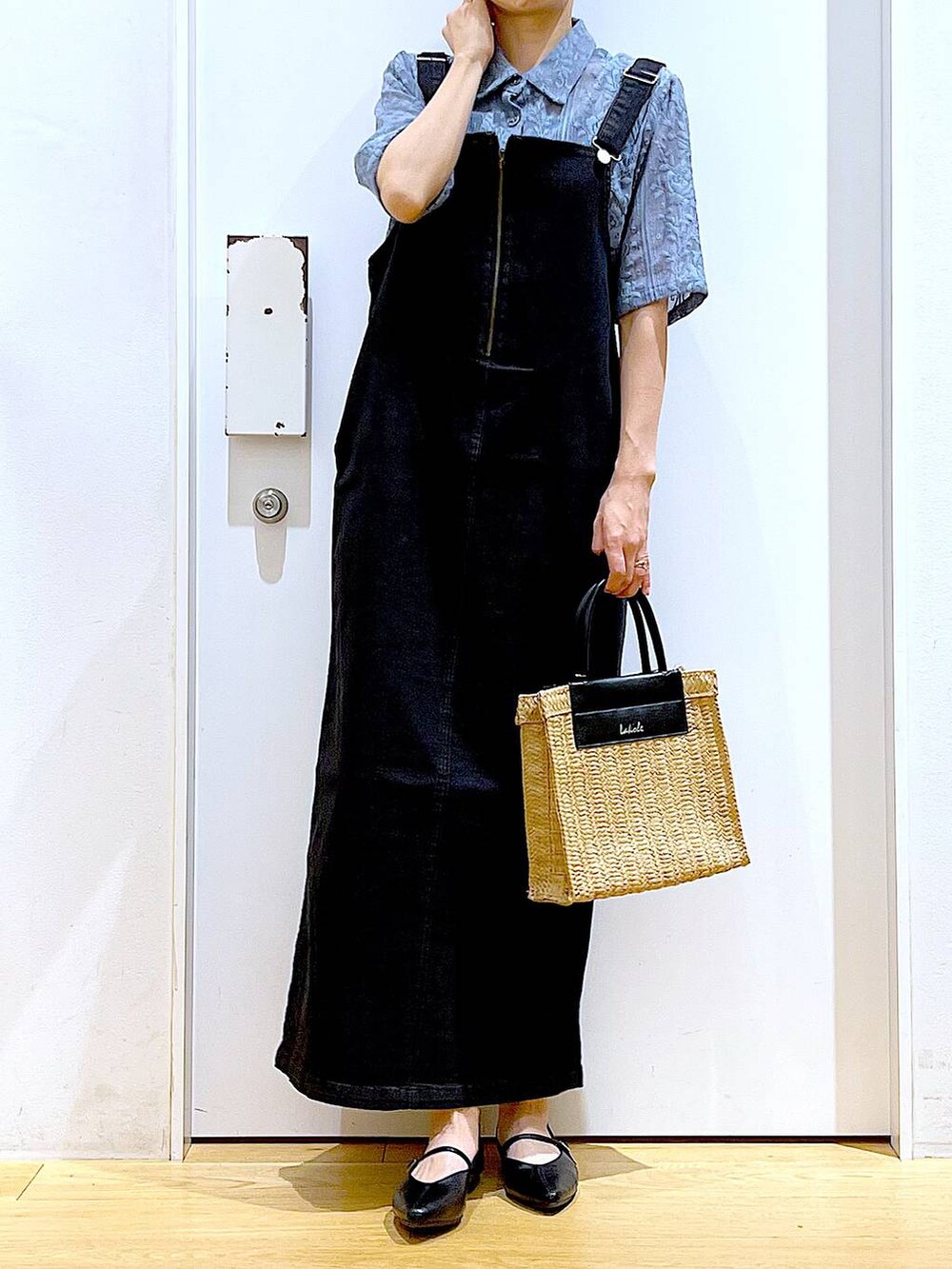 グレー系のジャンパースカート、ブラック系のパンプス、ベージュ系のショルダーバッグを着用したレディースの夏コーディネートの6枚目の写真