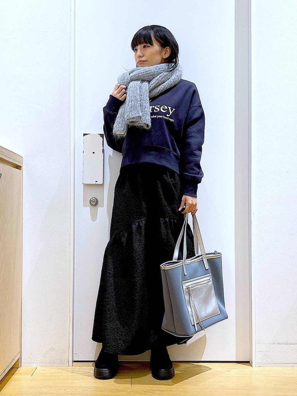 グレー系のトートバッグ、ブラック系のブーツ、グレー系のスウェットを着用したレディースの冬コーディネートの2枚目の写真