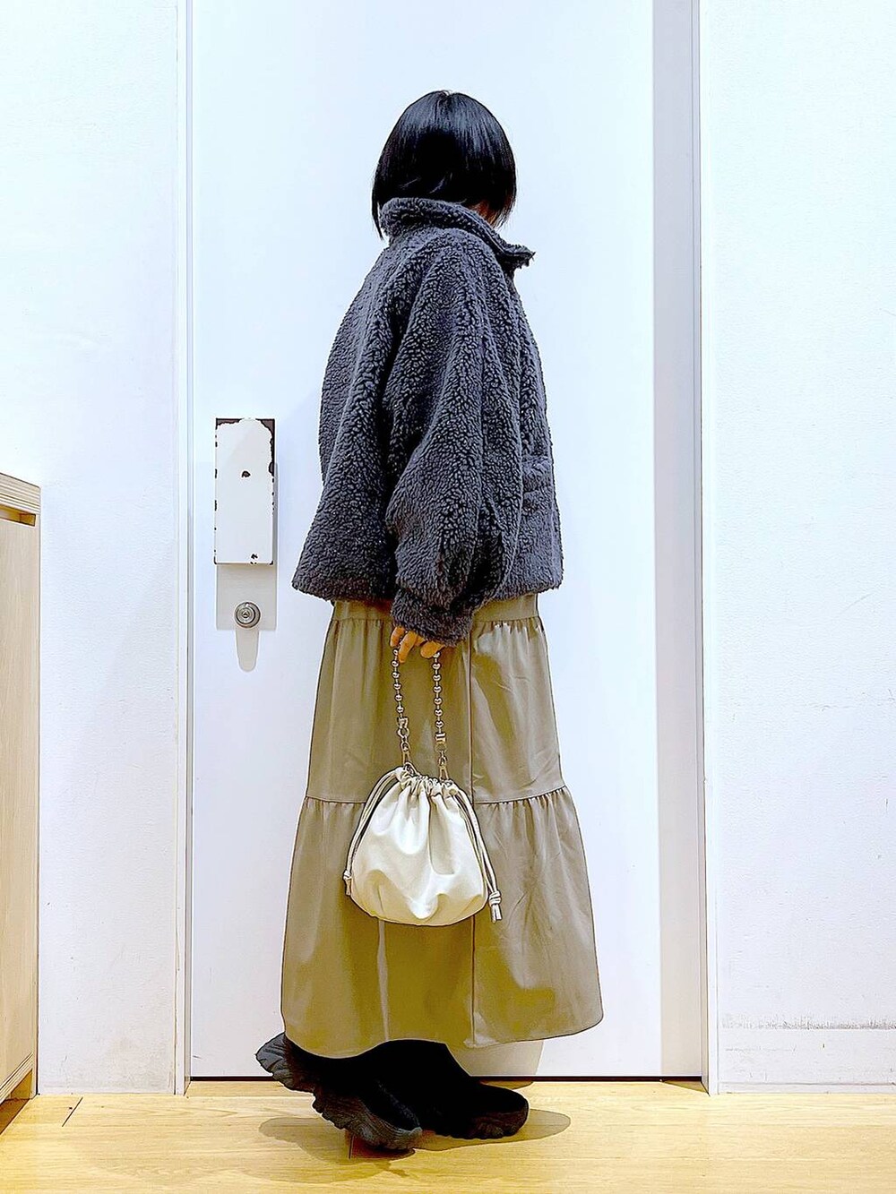 ベージュ系のショルダーバッグ、ブラック系のブーツ、ブラウン系のワンピースを着用したレディースの冬コーディネートの4枚目の写真