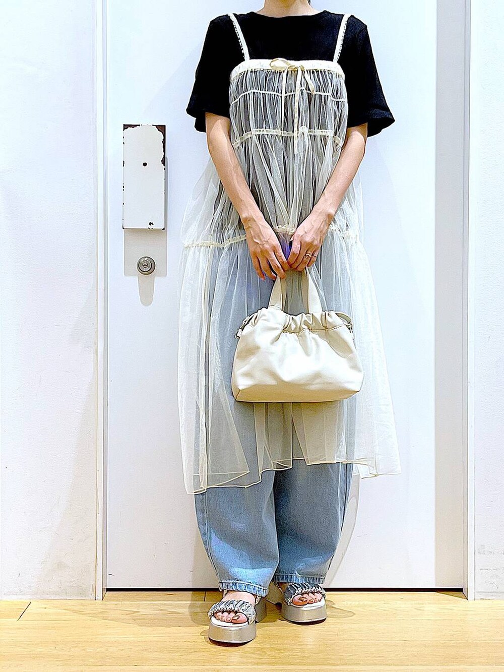 ブルー系のデニムパンツ、ホワイト系のショルダーバッグ、ブラック系のTシャツ/カットソーを着用したレディースの夏コーディネートの6枚目の写真