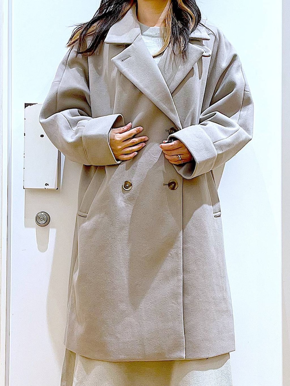 グレー系のステンカラーコート、ホワイト系のショルダーバッグ、グレー系のスカートを着用したレディースの冬コーディネートの7枚目の写真