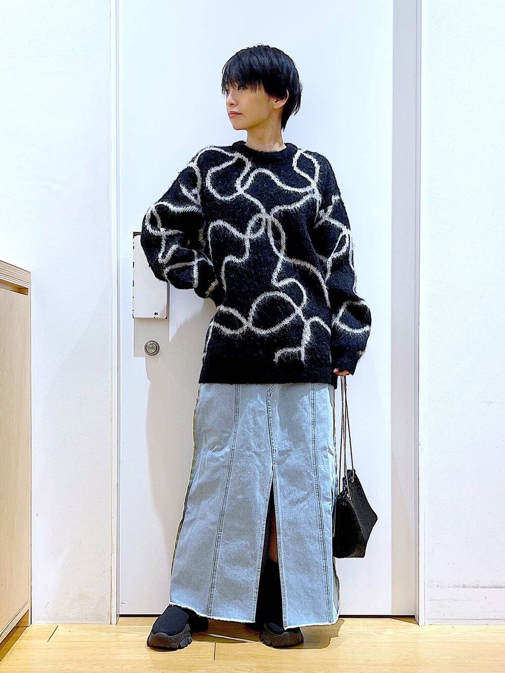 ブルー系のデニムスカート、ブラック系のブーツ、ブラック系のショルダーバッグを着用したレディースの冬コーディネートの2枚目の写真