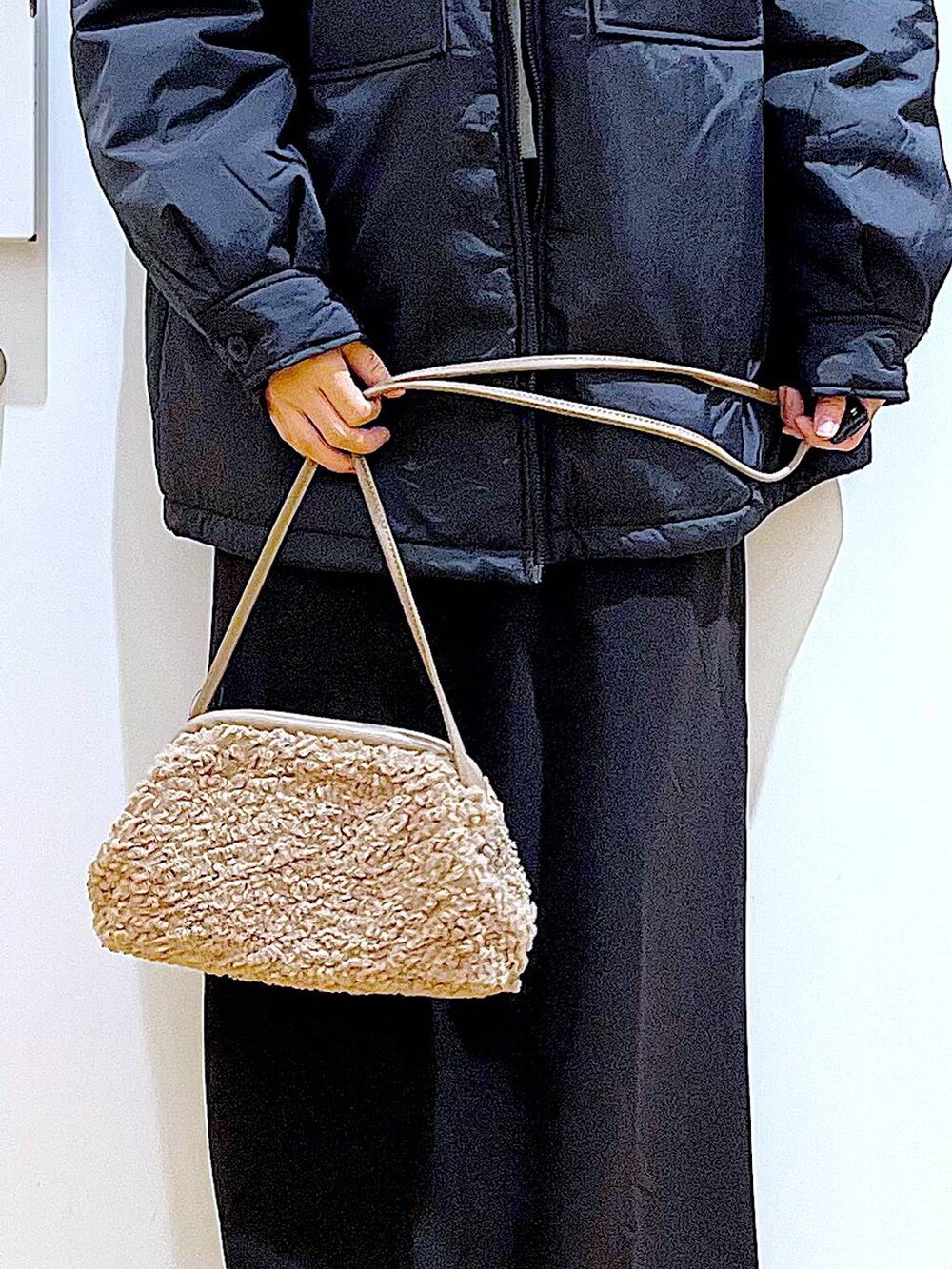 ブラック系のブルゾン、ブラック系のブーツ、ブラウン系のクラッチバッグを着用したレディースの冬コーディネートの9枚目の写真