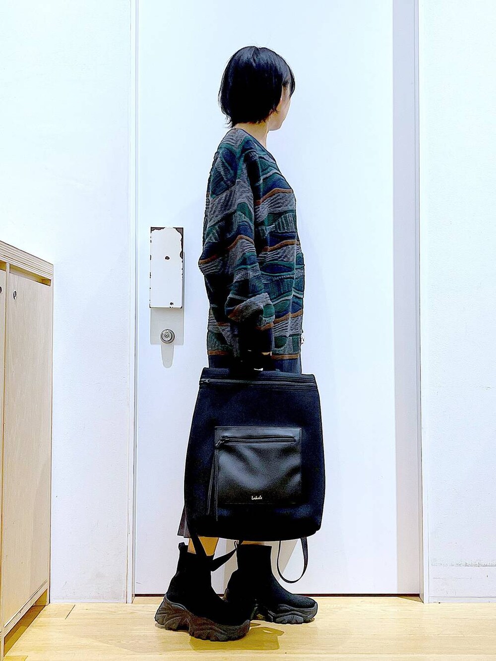 ブラック系のバックパック/リュック、ブラック系のブーツ、グレー系のスカートを着用したレディースの秋コーディネートの4枚目の写真