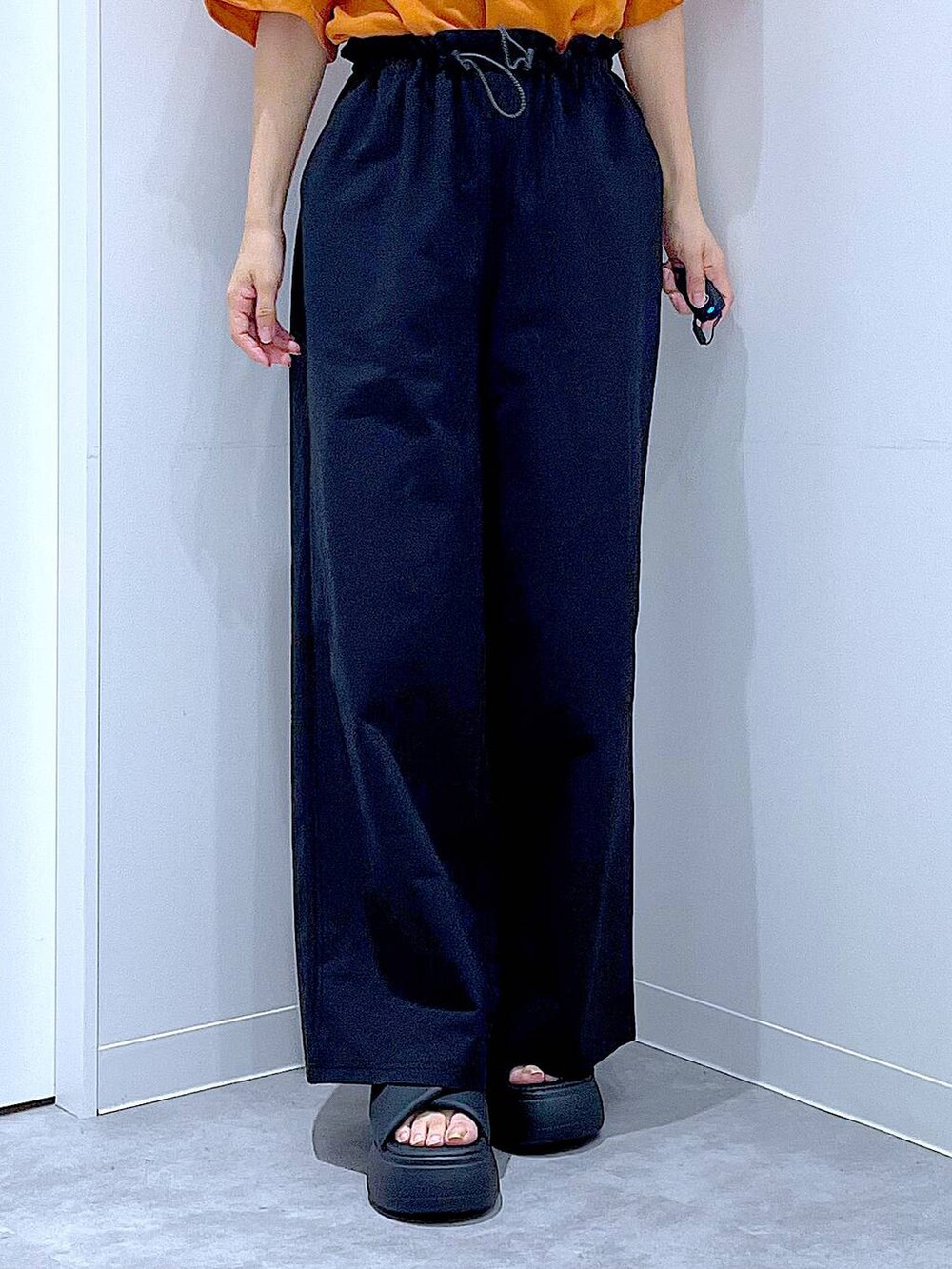 ベージュ系のショルダーバッグ、ブラック系のサンダル、オレンジ系のTシャツ/カットソーを着用したレディースの夏コーディネートの8枚目の写真