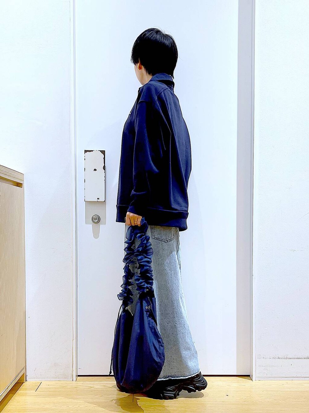 ブルー系のショルダーバッグ、ブラック系のブーツ、ブルー系のデニムスカートを着用したレディースの春コーディネートの3枚目の写真