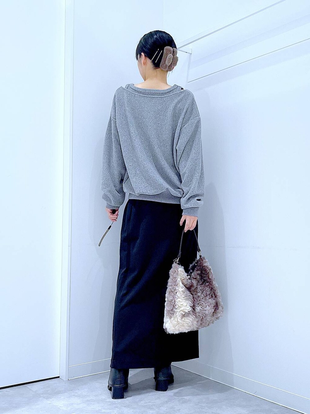 ブラック系のスカート、ブラック系のブーツ、ブラウン系のショルダーバッグを着用したレディースの冬コーディネートの5枚目の写真